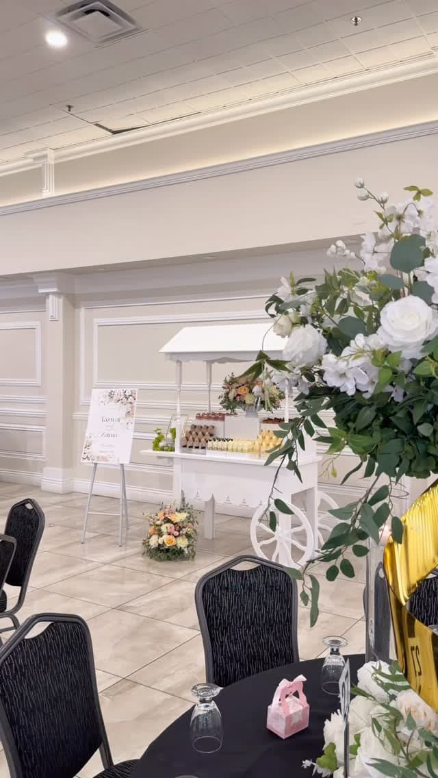 White Cart & Co. dessert cart styled with fresh florals in a ballroom reception, with a welcome sign beside it