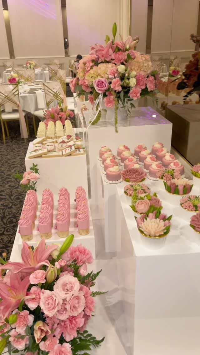 Flower-shaped macarons and pink mini cakes styled with fresh florals on a Cart & Co. dessert display