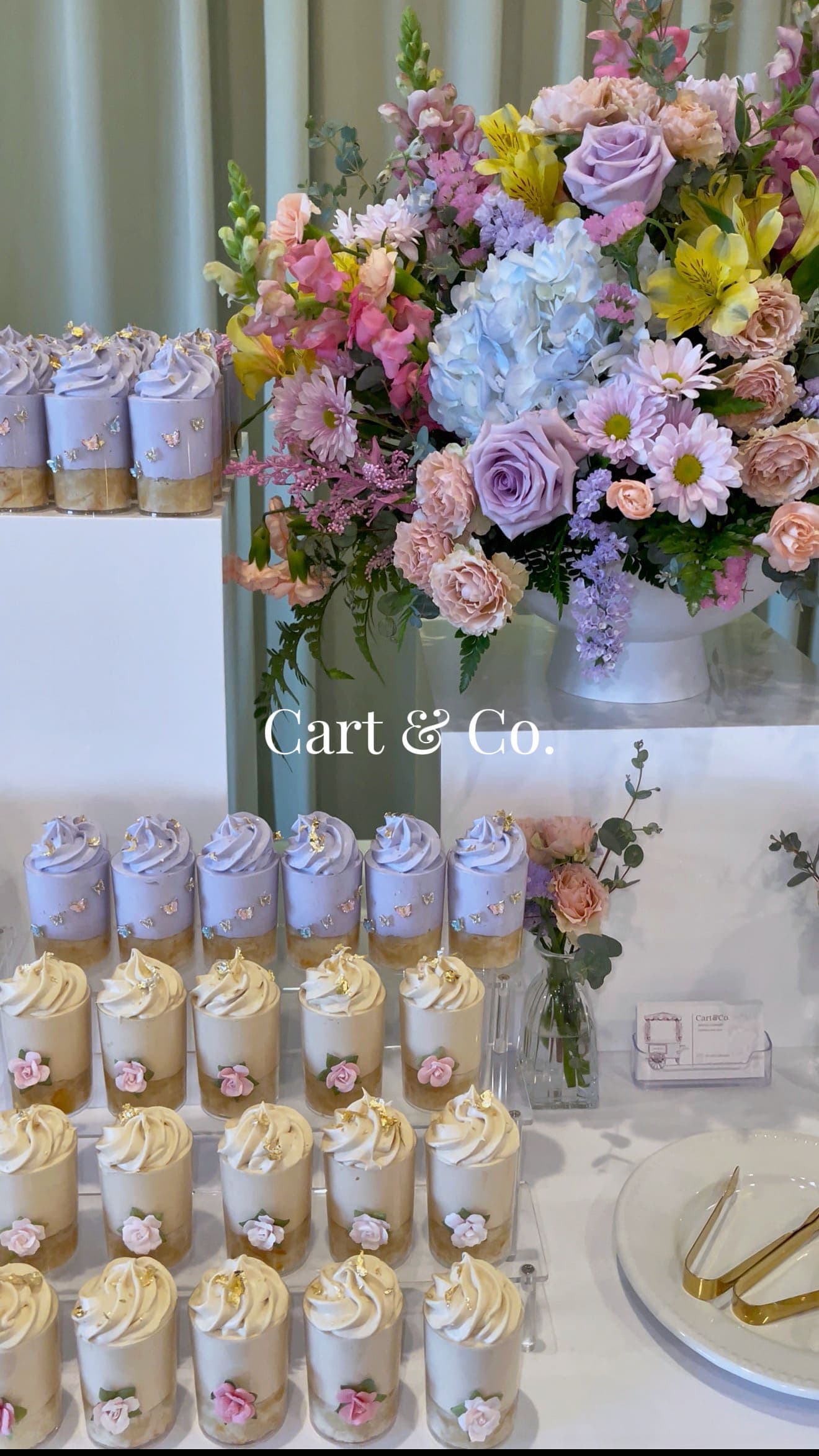 Lavender butterfly-topped mousse cups beside a pastel rose, hydrangea and alstroemeria arrangement
