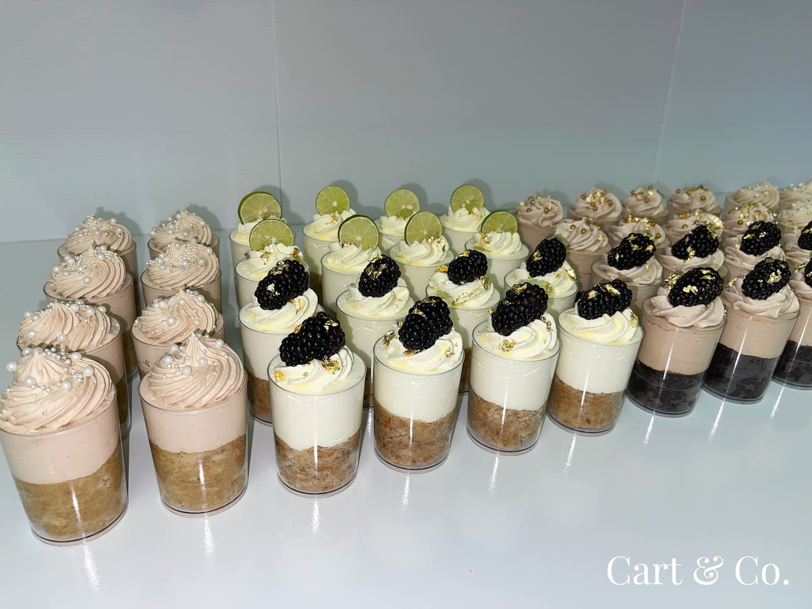 Rows of lime and blackberry mousse cups finished with gold leaf, styled in a Cart & Co. dessert display