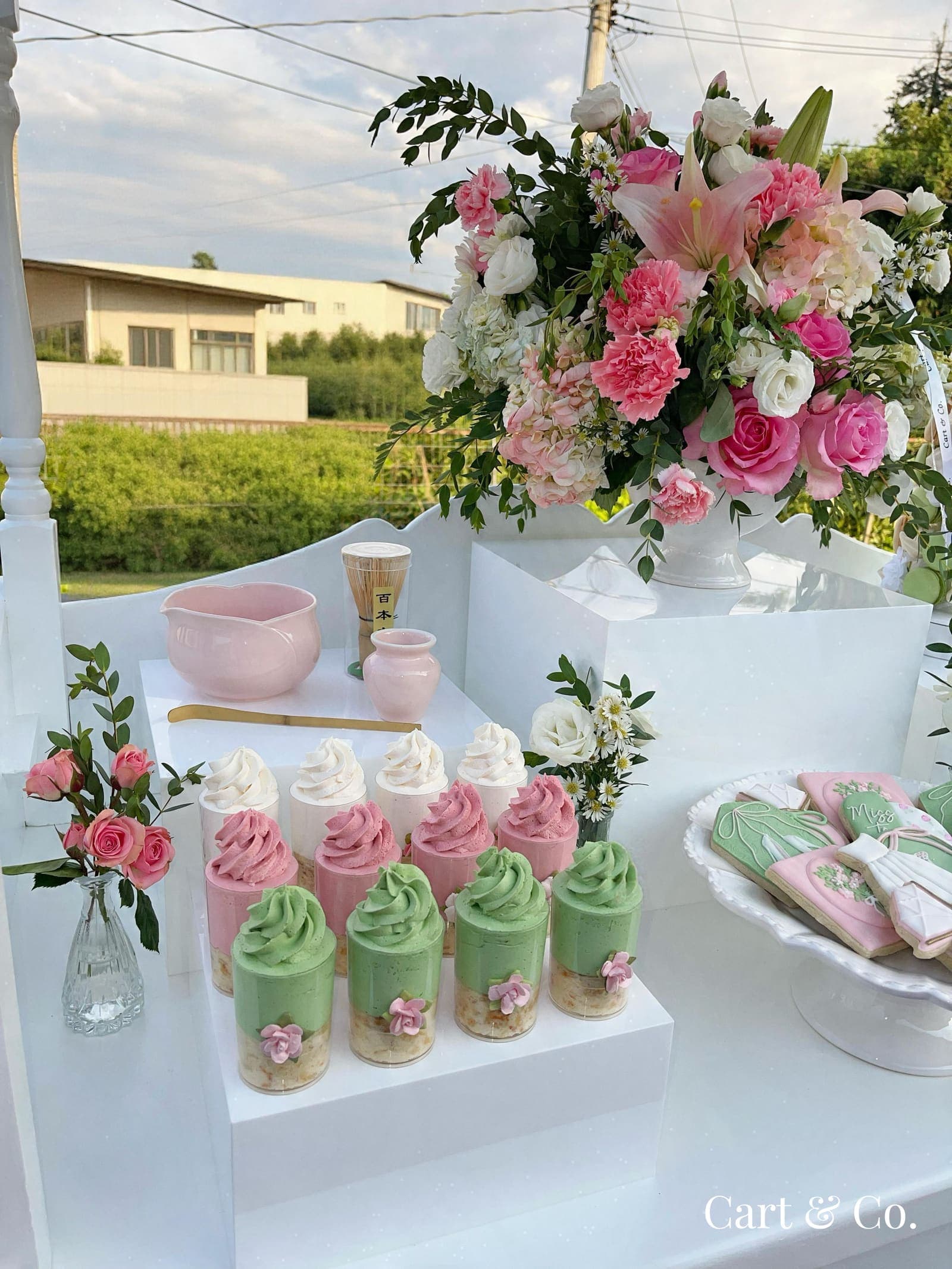 A matcha whisk and pink ceramic bowl beside pink and green mousse cups, styled for a 'Perfect Matcha' bridal shower