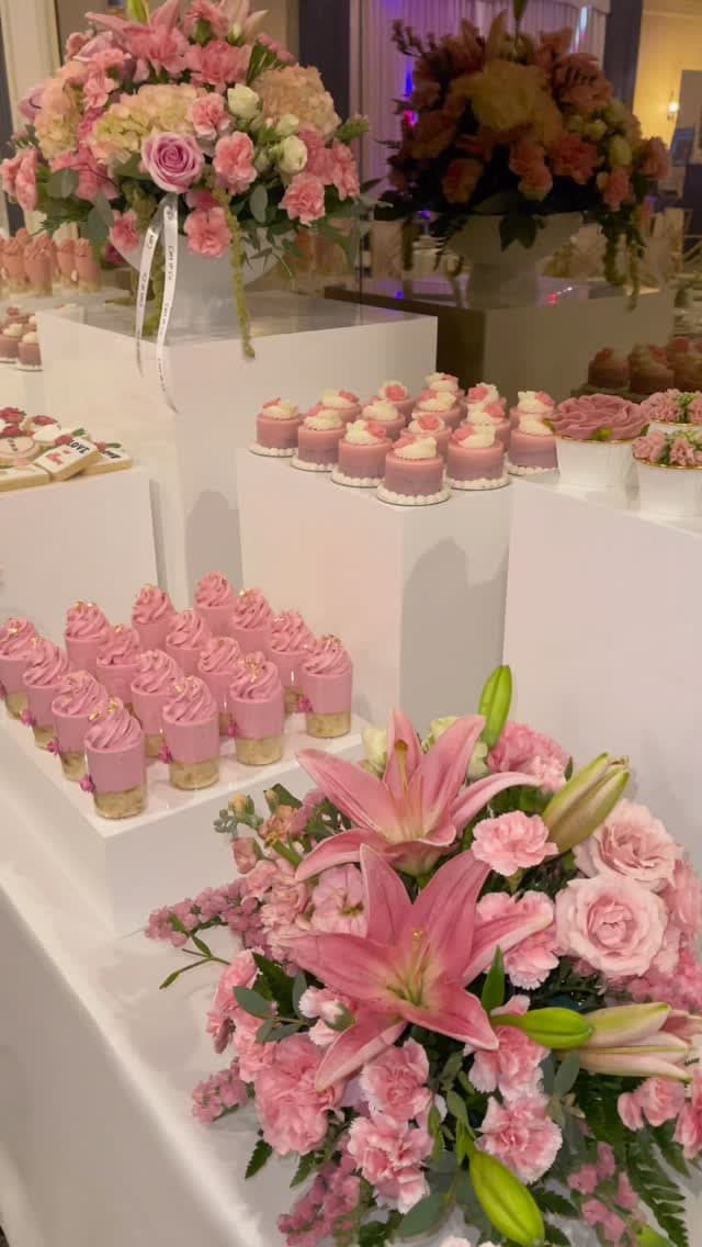 Curated pink grazing table with mousse cups, mini cakes and a lush lily and rose arrangement styled by Cart & Co.