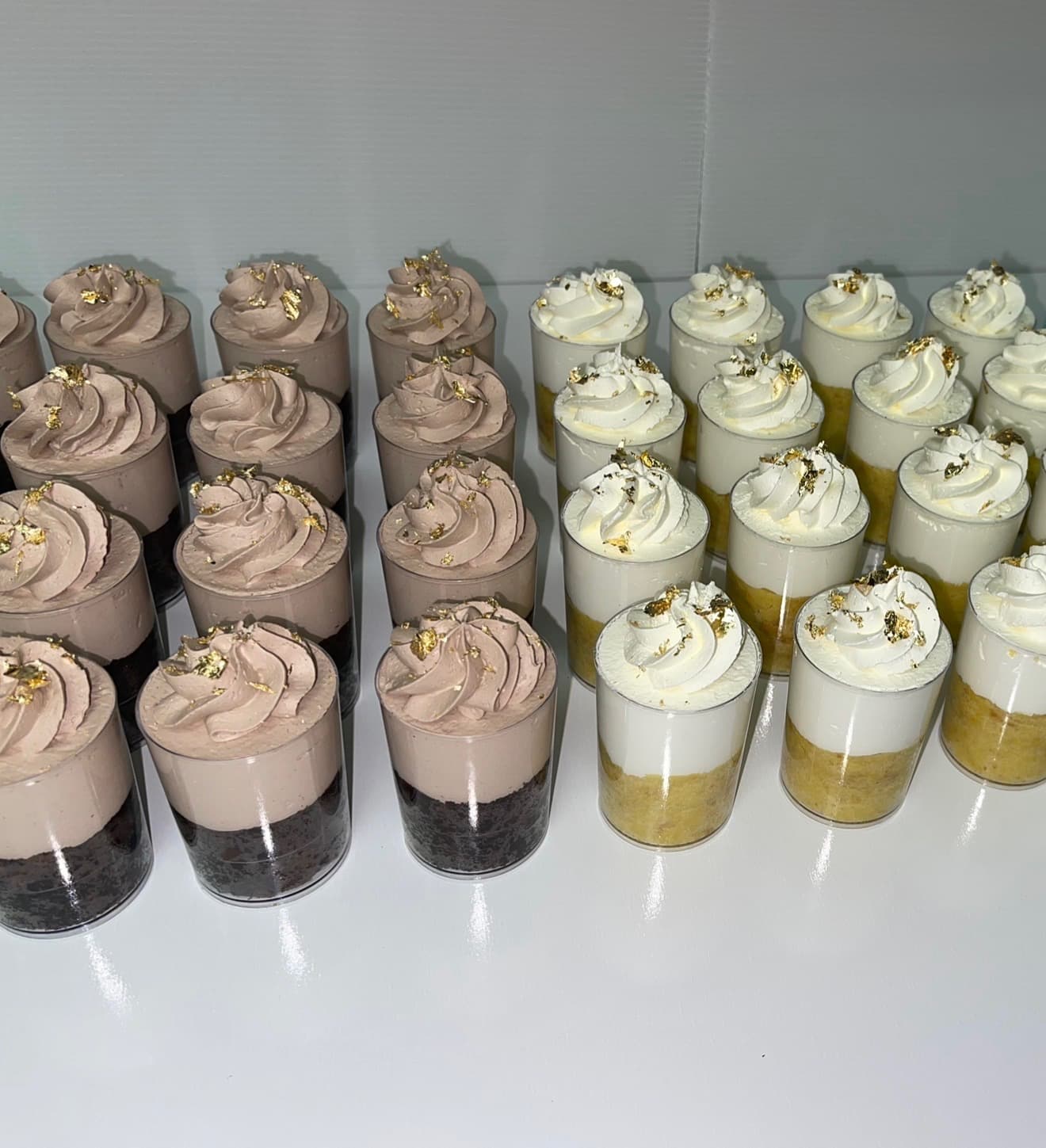 Rows of chocolate and vanilla mousse shooter cups finished with gold leaf, ready for a Cart & Co. Catering Pickup Menu order